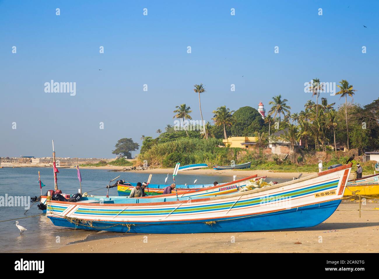 Fischerboote am Strand mit Tangasseri Leuchtturm im Hintergrund, Kollam, Kerala, Indien, Asien Stockfoto