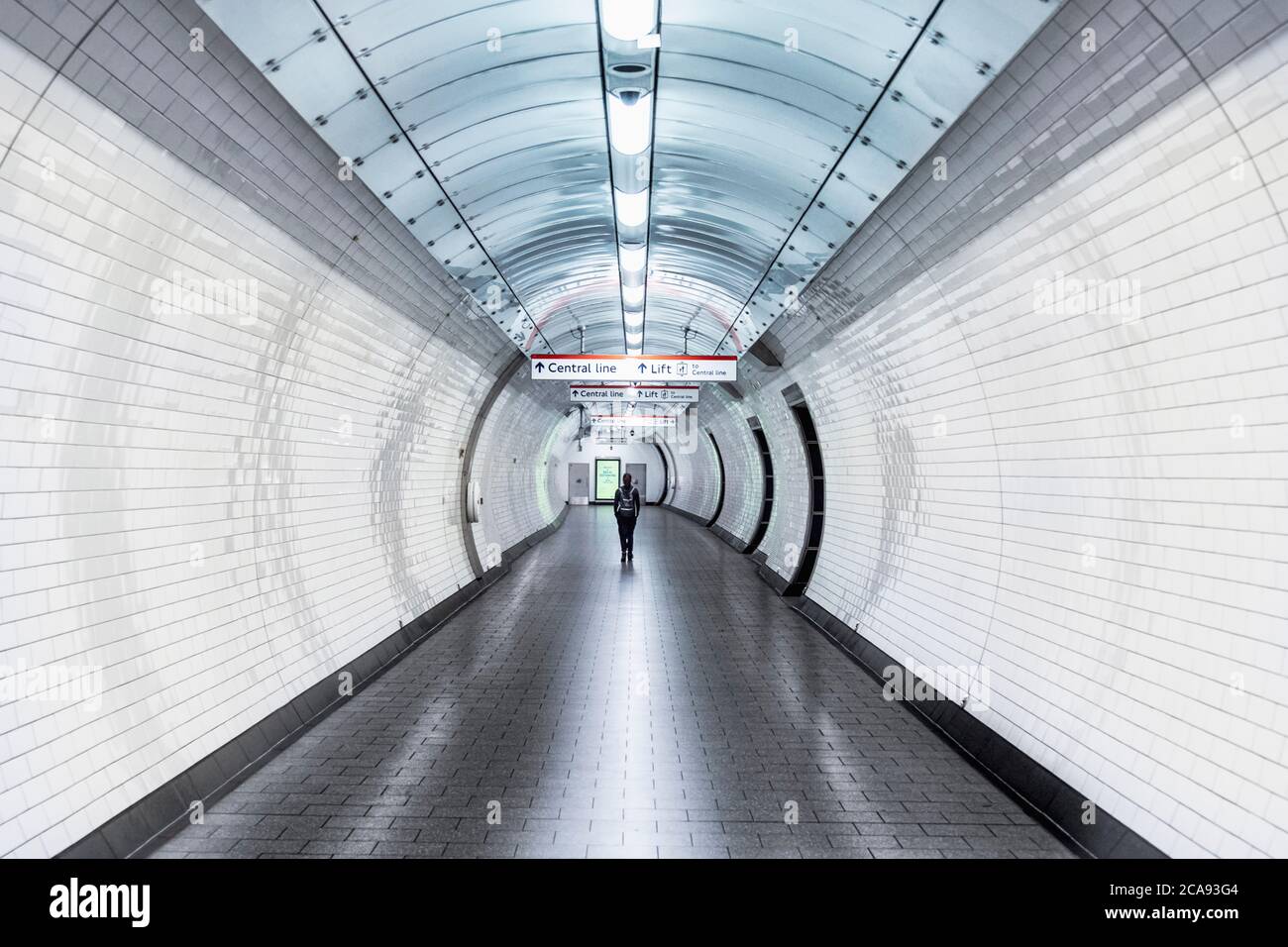 Eine einzelne Person, die während der Coronavirus-Sperre in einer U-Bahn-Station einen Korridor entlang läuft, London, England, Großbritannien, Europa Stockfoto