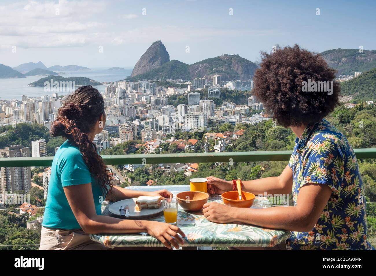 Ein multiethnisches Paar, das zusammen frühstücken und den Blick auf den Zuckerhut und die Skyline von Rio, Rio de Janeiro, Brasilien und Südamerika schweifen lässt Stockfoto