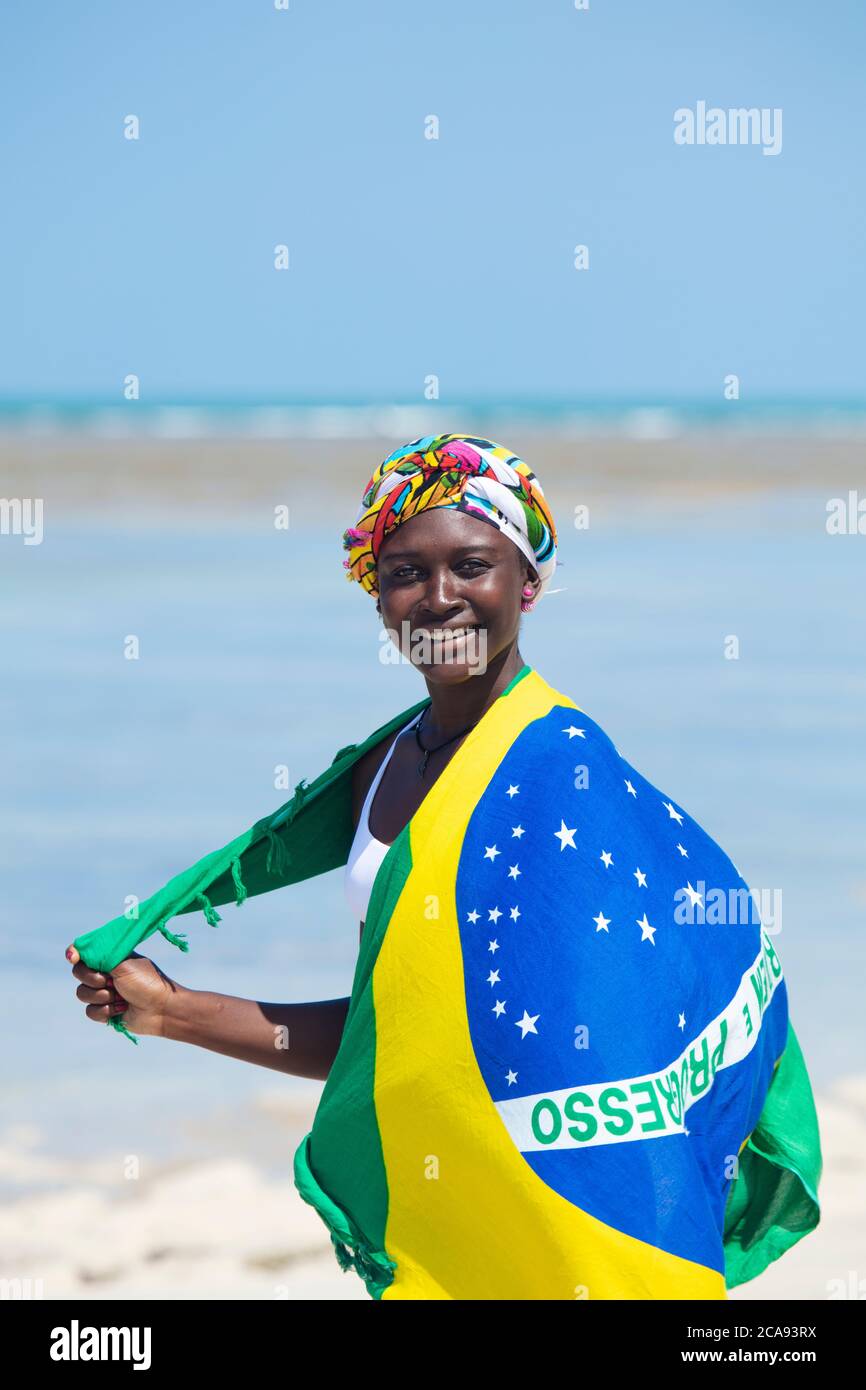 Eine junge schwarze Brasilianerin mit einem Kopftuch und einem Wrap mit der Nationalflagge, lächelnd und mit Blick auf die Kamera, Brasilien, Südamerika Stockfoto
