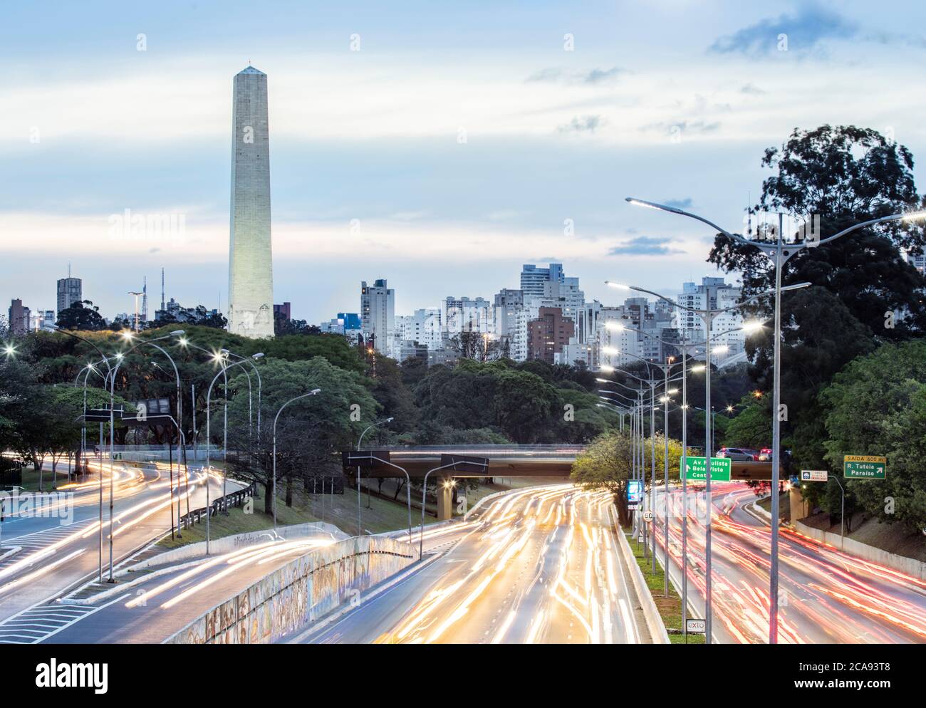 Rush Hour Ampelwege auf 23 de Maio Avenue, die Skyline und der Obelisk der Helden in Ibirapuera Park, Sao Paulo, Brasilien, Südamerika Stockfoto