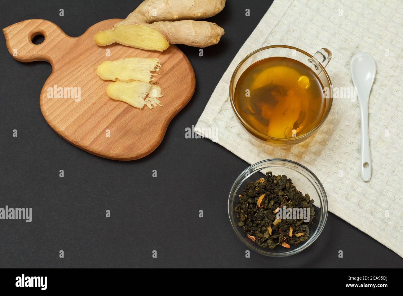 Gesundheit Heilmittel Lebensmittel für Erkältung und Grippe-Linderung. Tasse Tee, Ingwer und eine Glasschüssel mit getrockneten Teeblättern auf schwarzem Hintergrund. Draufsicht. Lebensmittel, Die Stockfoto