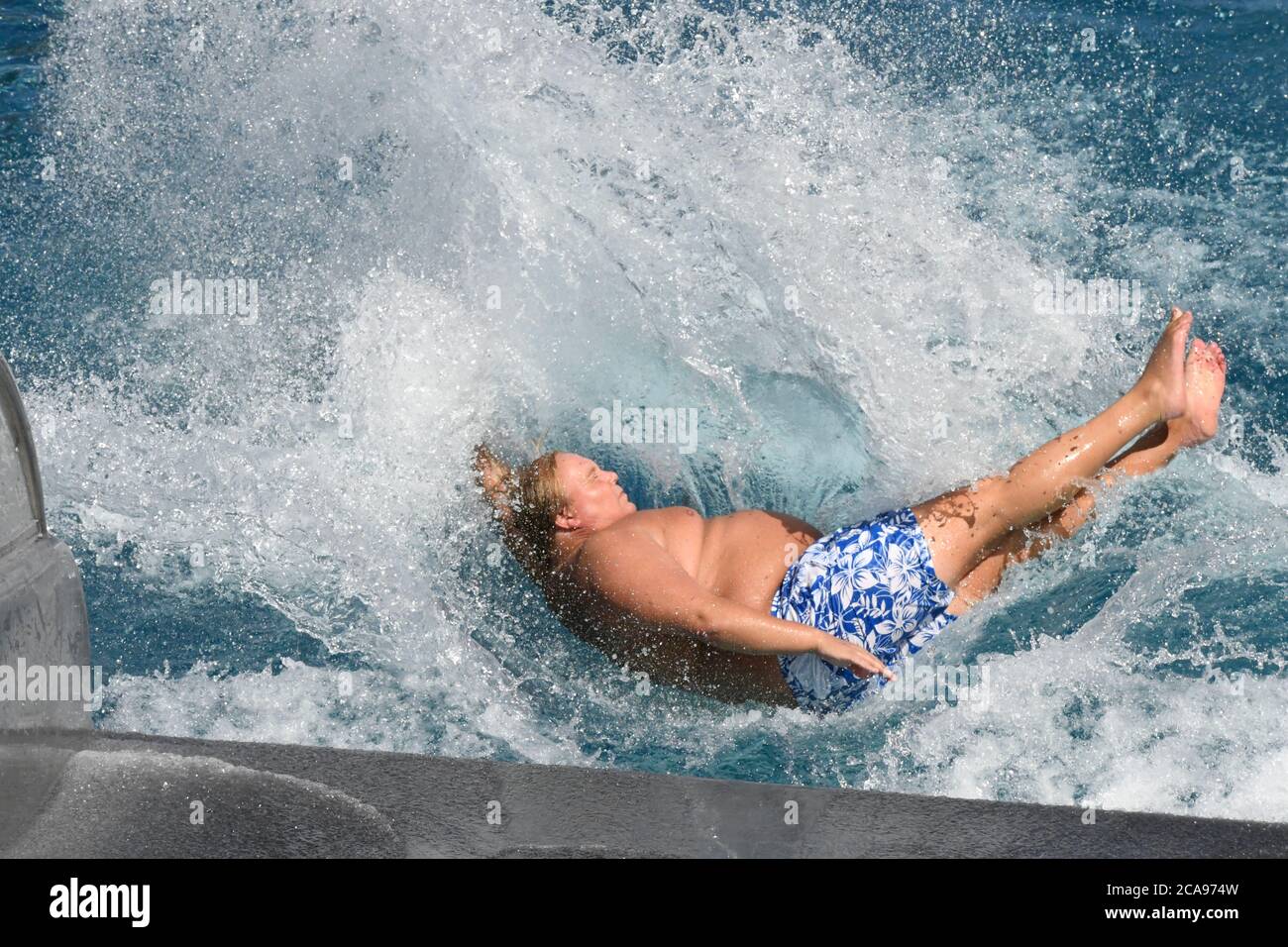 Köln, Deutschland. August 2020. Ein Mann nutzt die Wasserrutsche des Stadionpools und kühlt ab. Meteorologen sagen eine Hitzewelle in den nächsten Tagen mit Temperaturen weit über 30 Grad voraus. Quelle: Roberto Pfeil/dpa/Alamy Live News Stockfoto