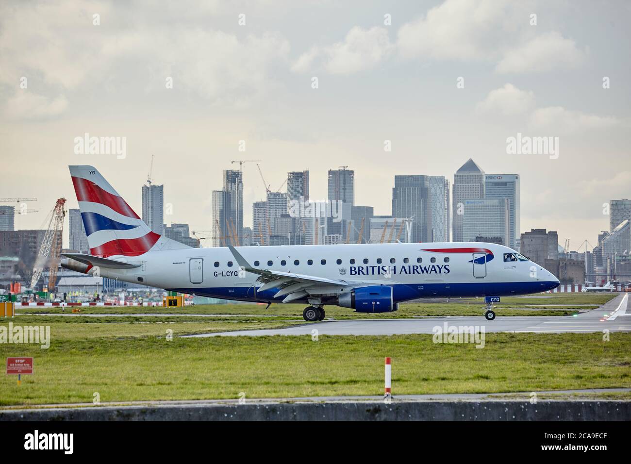 British Aiways Embrear 170 Flugzeug rollt am London City Airport mit der Londoner Skyline im Hintergrund. Stockfoto