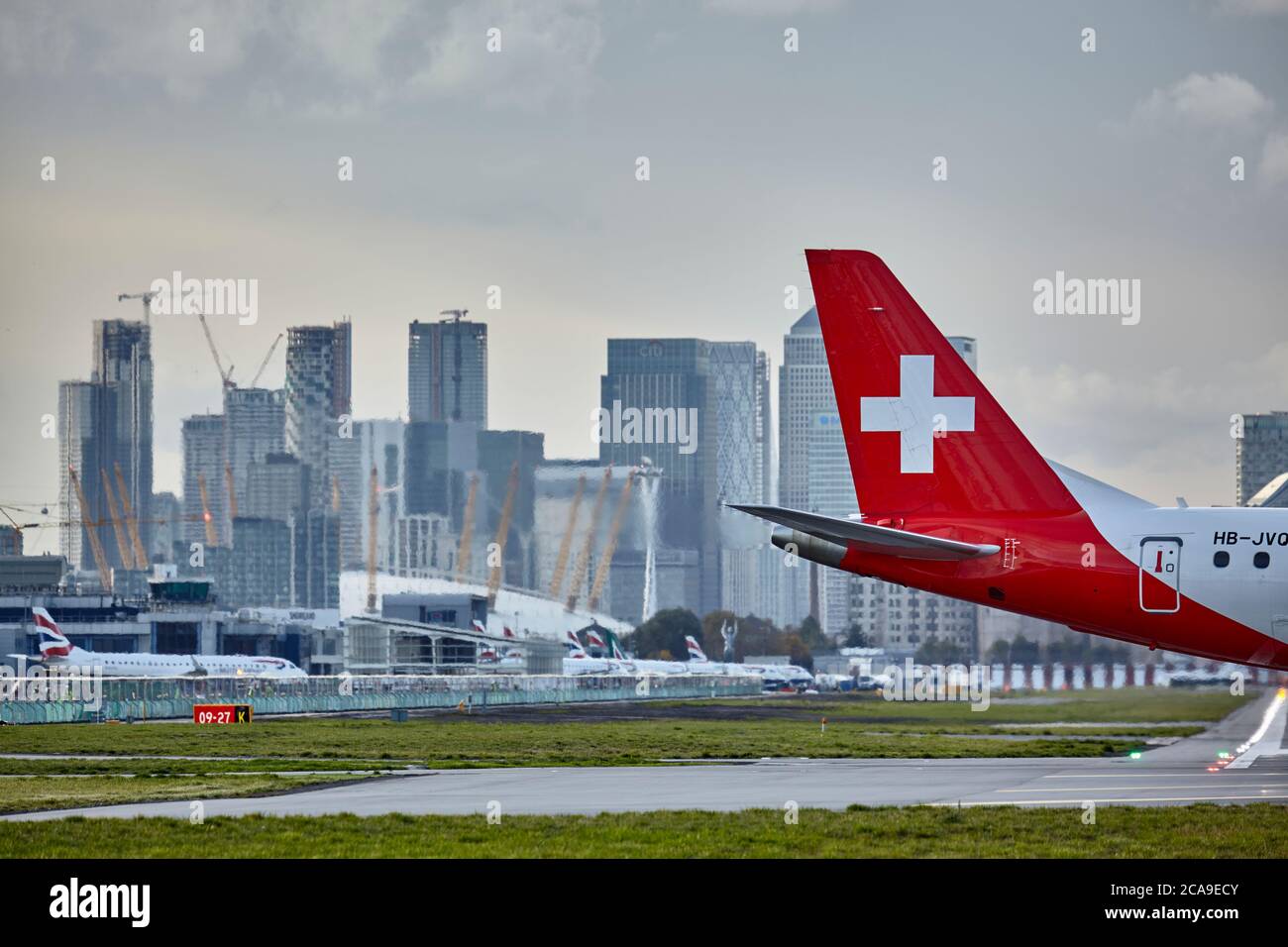 Schweif eines rollenden Swiss Air-Flugzeugs am London City Airport mit der Londoner Skyline im Hintergrund. Stockfoto