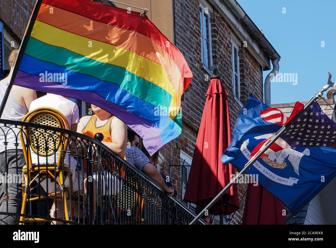 New Orleans - 04/15/2018 : Menschen genießen Getränke auf einem Café-Balkon unter der LGBT-Flagge Stockfoto