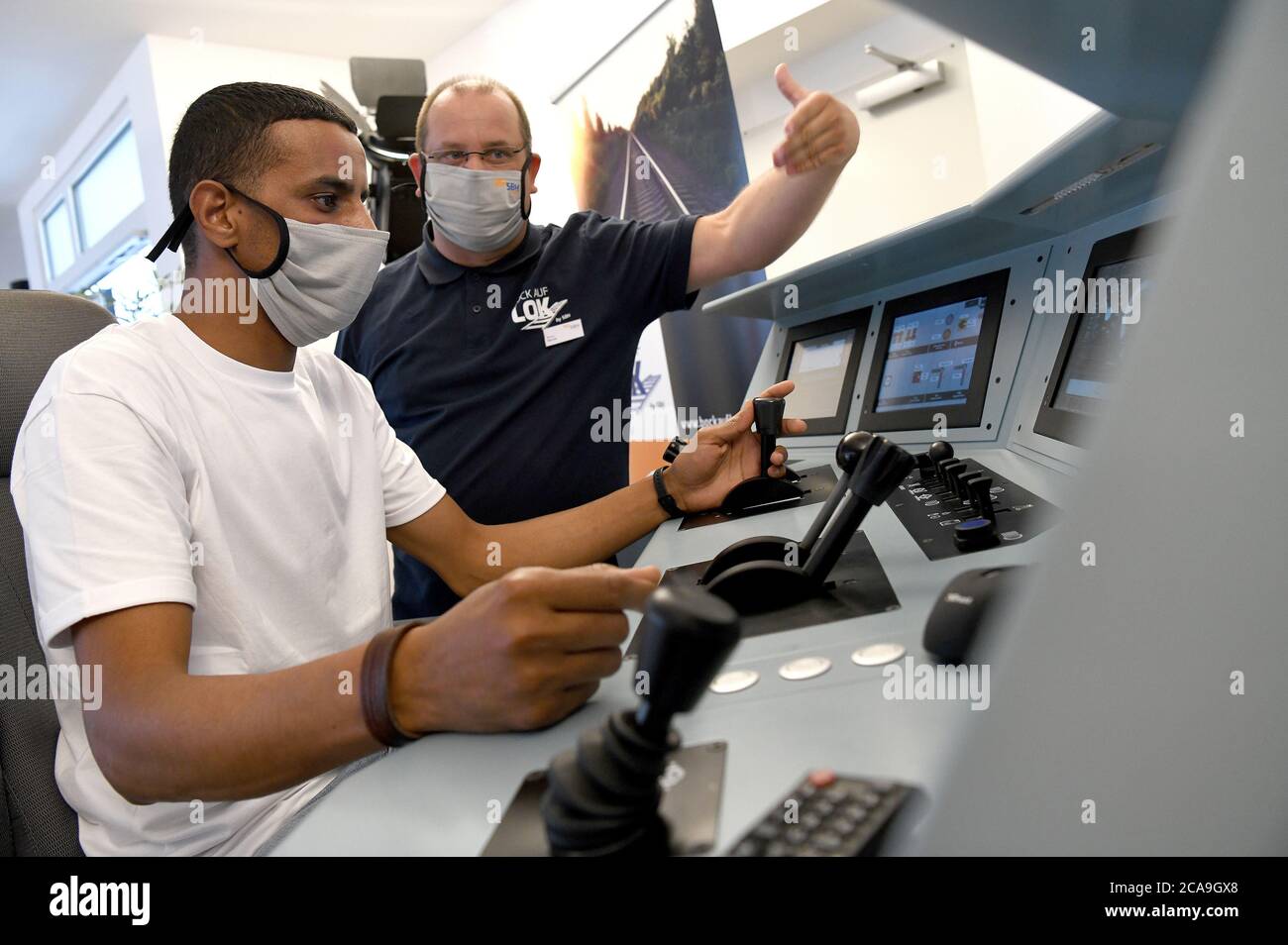 Gelsenkirchen, Deutschland. August 2020. Adel Lhababi, (l) Auszubildender aus Marokko und Sven Warda, Ausbilder in einem Pilotkurs für Zugführertraining für Migranten im Zugsimulator. Die 13 Teilnehmer kommen aus sieben Nationen. In den nächsten fünf Jahren werden rund 1700 Zugfahrer aus NRW fehlen. Quelle: Caroline Seidel/dpa/Alamy Live News Stockfoto