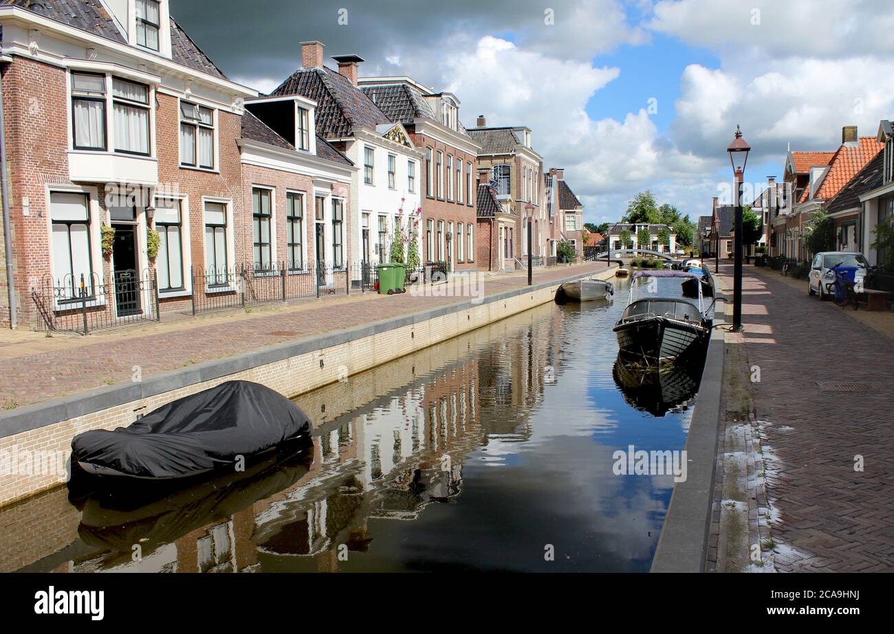 Blick auf die malerische Stadt Kollum in Friesland in den Niederlanden an einem sonnigen Sommermorgen. Blick auf die Trekvaart Wasserstraße, Boote und das Wasser ho Stockfoto