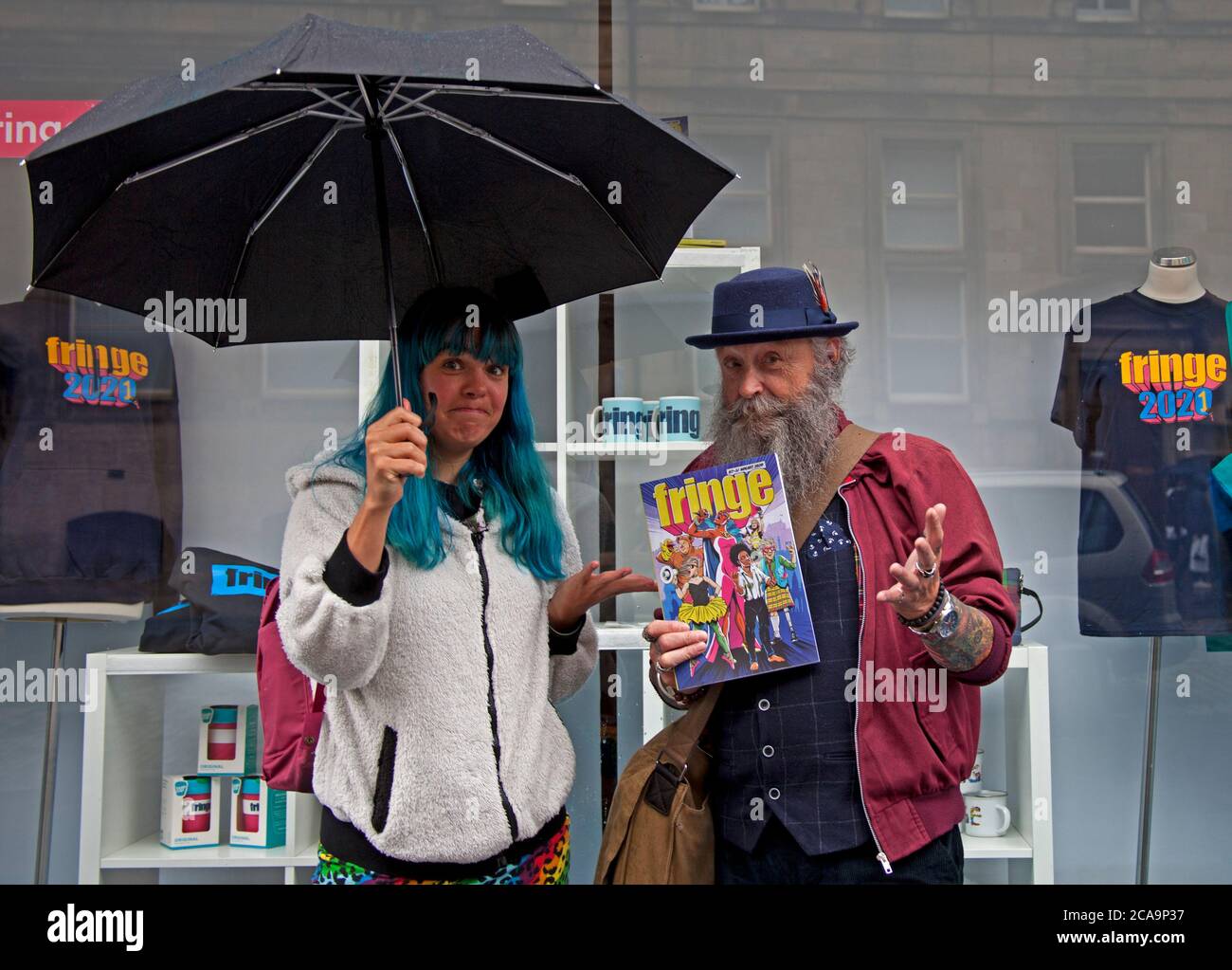 Royal Mile Edinburgh, Schottland, Großbritannien. August 2020. Im Bild: Lokales Ehepaar Jimmy und Nora mit dem bunten 2020 Fringe Progamme Cover, das leere Seiten im Inneren hat, da der Druck nicht begonnen hat, als die Covid-19, Die Coronavirus-Pandemie traf Großbritannien zu Beginn des Jahres, und die Fringe, die am 7. August hätte beginnen sollen, und alle anderen geplanten jährlichen Festivals mussten absagen. Stockfoto