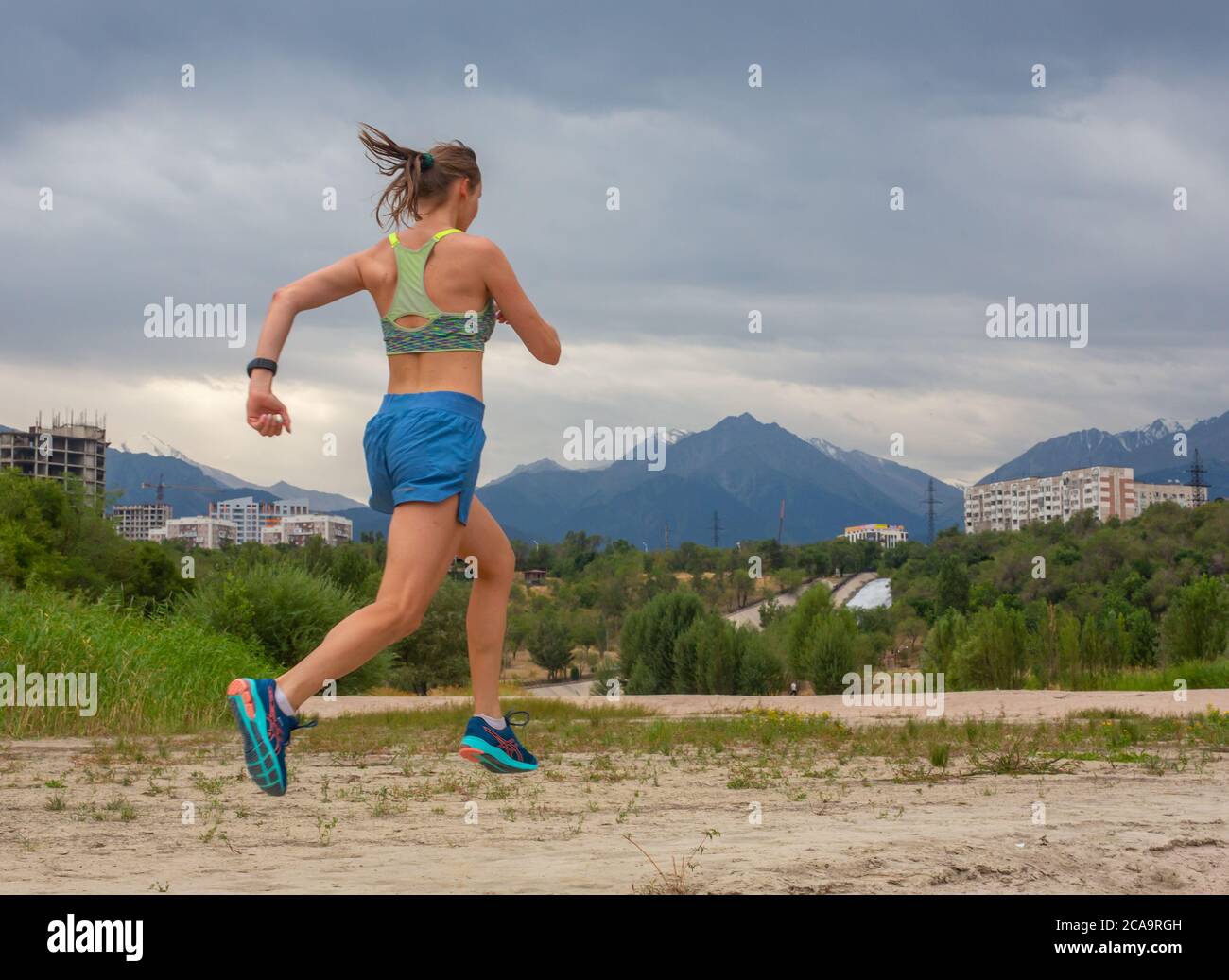Laufen im Stadtpark. Frau Läuferin draußen beim Joggen, Blick auf die Berge im Hintergrund. Stockfoto