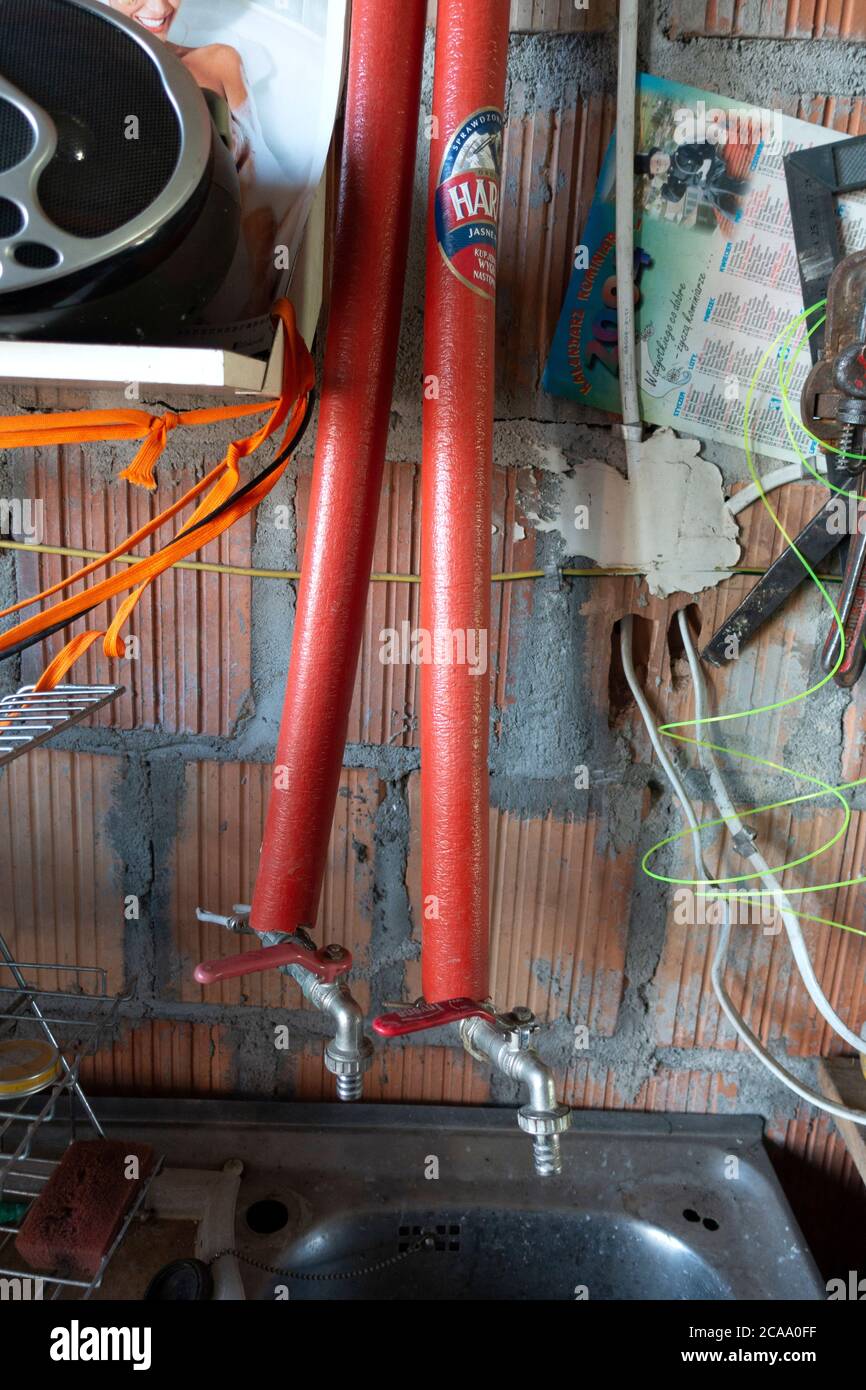 Rote Rohrabdeckungen an heißen und kalten Wasserhähnen in der Garage. Zawady Gmina Rzeczyca Polen Stockfoto