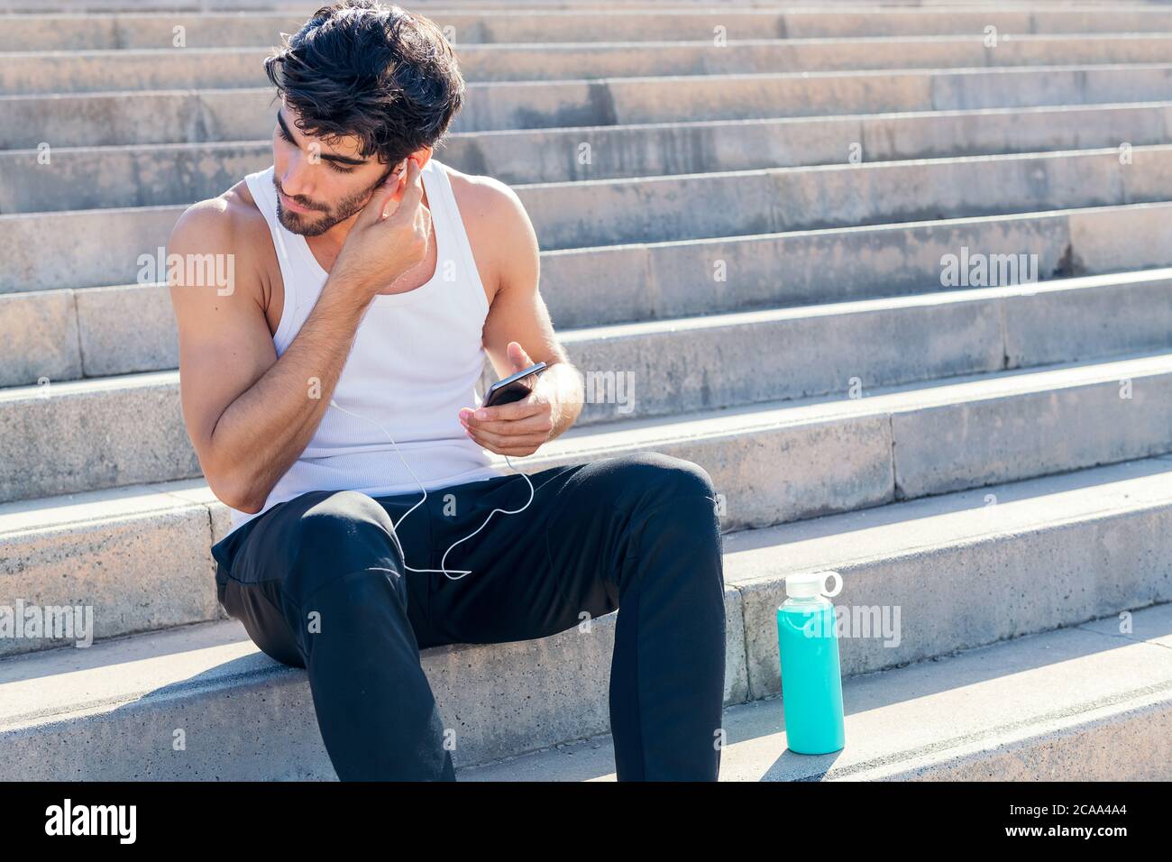 Sportlicher Mann setzt Kopfhörer auf, um Musik während des Trainings, urbanes Sportkonzept und gesunden Lebensstil zu hören, kopieren Raum für Text Stockfoto