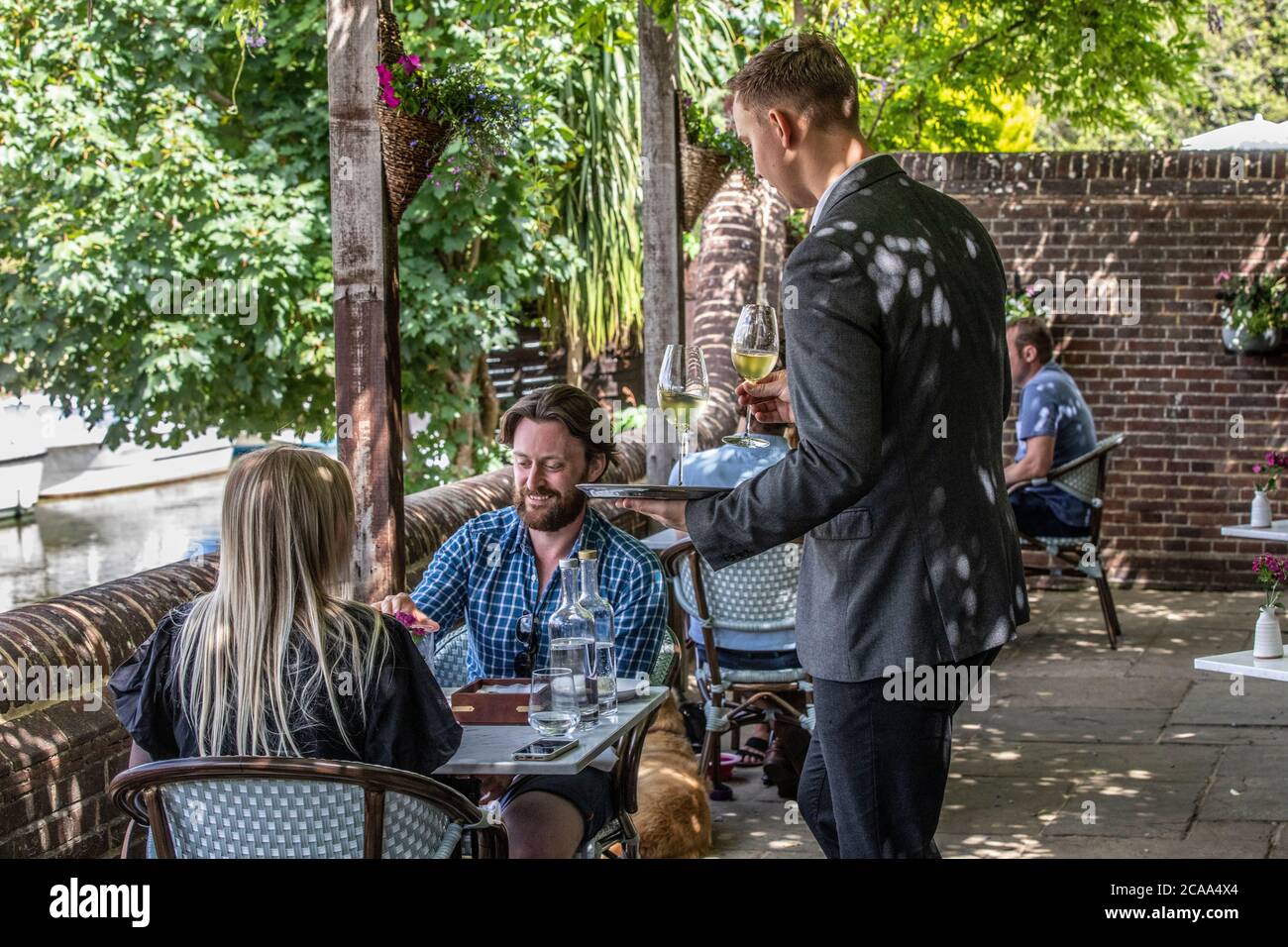 Leute sitzen auf der Terrasse am Fluss mit Blick auf den Great Stour Fluss und essen im Freien im Fordwich Arms, Fordwich, Kent, England, Großbritannien Stockfoto