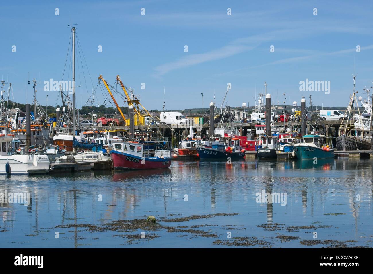 Trawler vertäuten im Hafen von Newlyn. Voll mit kleinen Fischerbooten und Seeschleppern an Liegeplätzen entlang Pontons. Blauer Himmel Querformat. Stockfoto