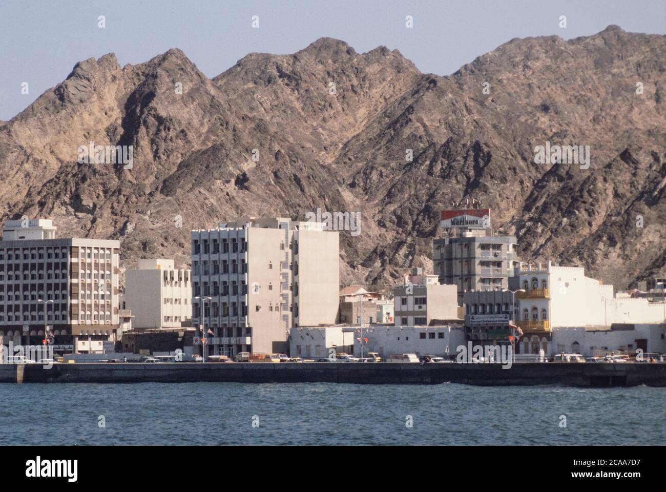 Archivbild: Das Sultanat Oman 1979, sieben Jahre nach der Machtübernahmen des Sultans Qaboos und der Modernisierung des Landes. Dies war noch eine Zeit, als der Tourismus in das Land in den Kinderschuhen steckte. Bild: Moderne Gebäude an der Muttrah Corniche mit schroffen Bergen in der Ferne. Quelle: Malcolm Park Stockfoto