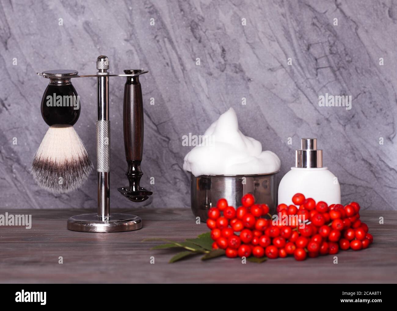 Rasiermesser, Pinsel, Schaum und Eberesche auf einem Holzhintergrund. Stockfoto