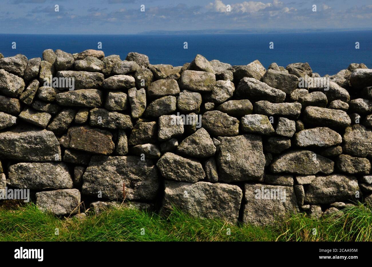 Zufällig verlegte Granitsteinwand auf der Insel Lundy im Bristol Kanal vor der Nordküste von Devon, die am Horizont sichtbar ist. Stockfoto