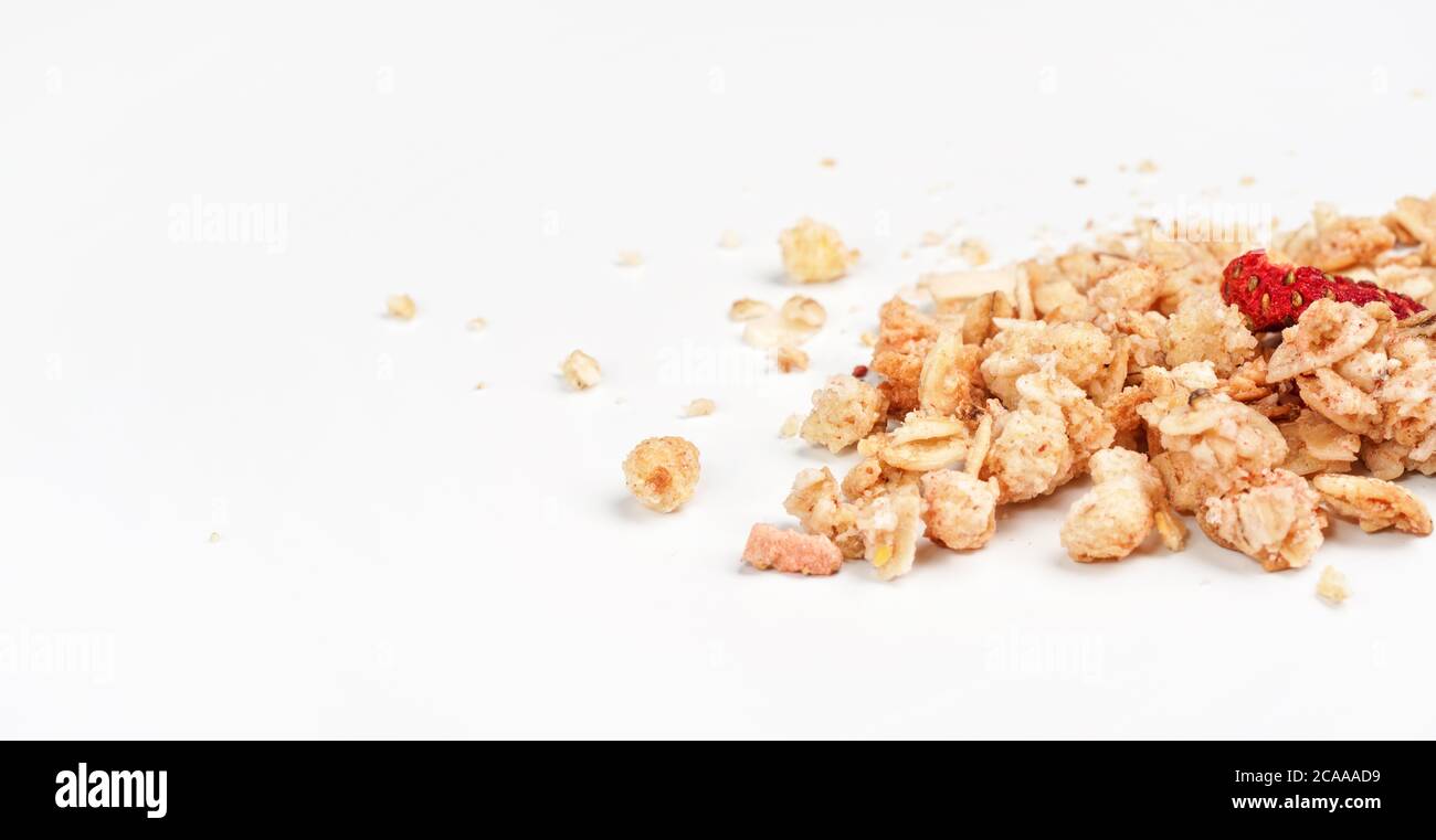 Müsli Flocken mit einer getrockneten Erdbeere, Nahaufnahme isoliert auf weißem Hintergrund Platz für Text links Stockfoto