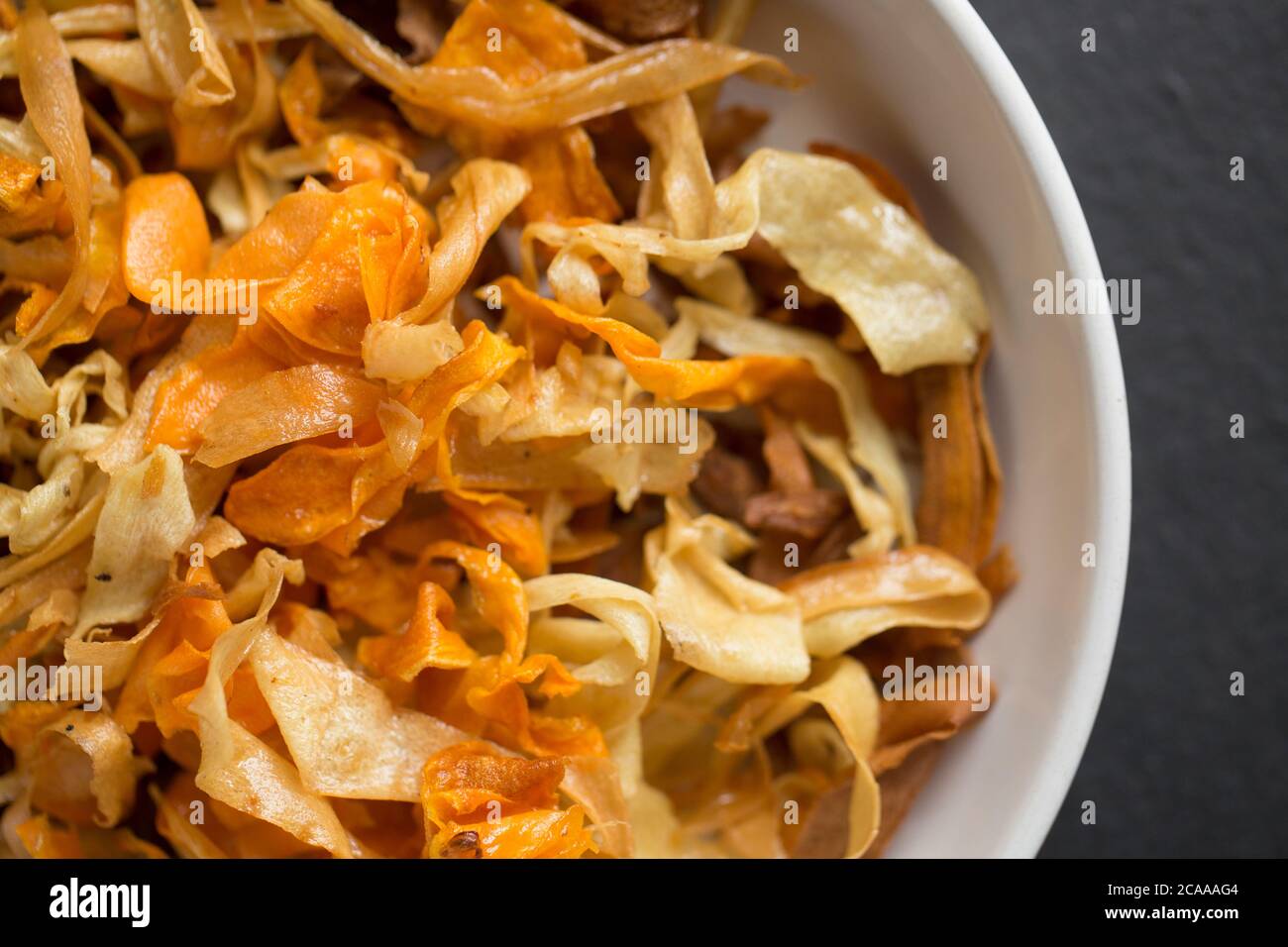 Eine große Schmorlvoll frittierter hausgemachter Chips aus Karotten, Pastinaken und Süßkartoffeln. Dorset England GB Stockfoto