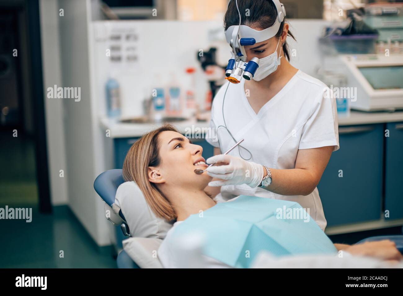 Junge Zahnarzt Arzt in weißen Uniform und spezielle Stirnlampe untersuchen  die Zähne des Patienten, loszuwerden, verdorbene Zähne Stockfotografie -  Alamy
