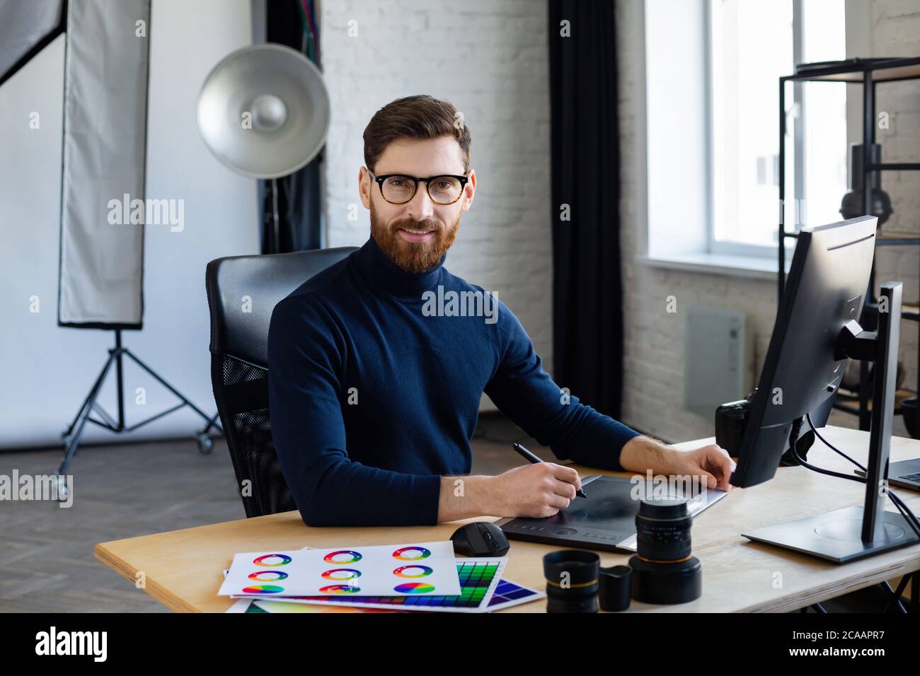 Retusche Bilder in speziellen Programm.Portrait von Grafikdesigner arbeiten im Büro mit Laptop, Monitor, Grafik Zeichnung Tablette und Farbpalette Stockfoto