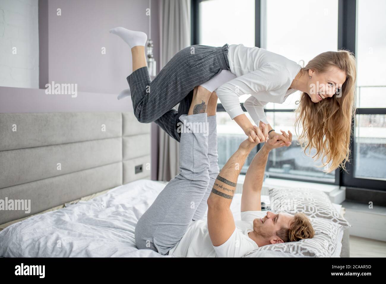 Mad Mann versucht, das Mädchen mit Beinen zu heben, lustige Zeit. Mann und Frau unterhalten sich gegenseitig. Seitenansicht Foto. Freizeit. Lifestyle Stockfoto