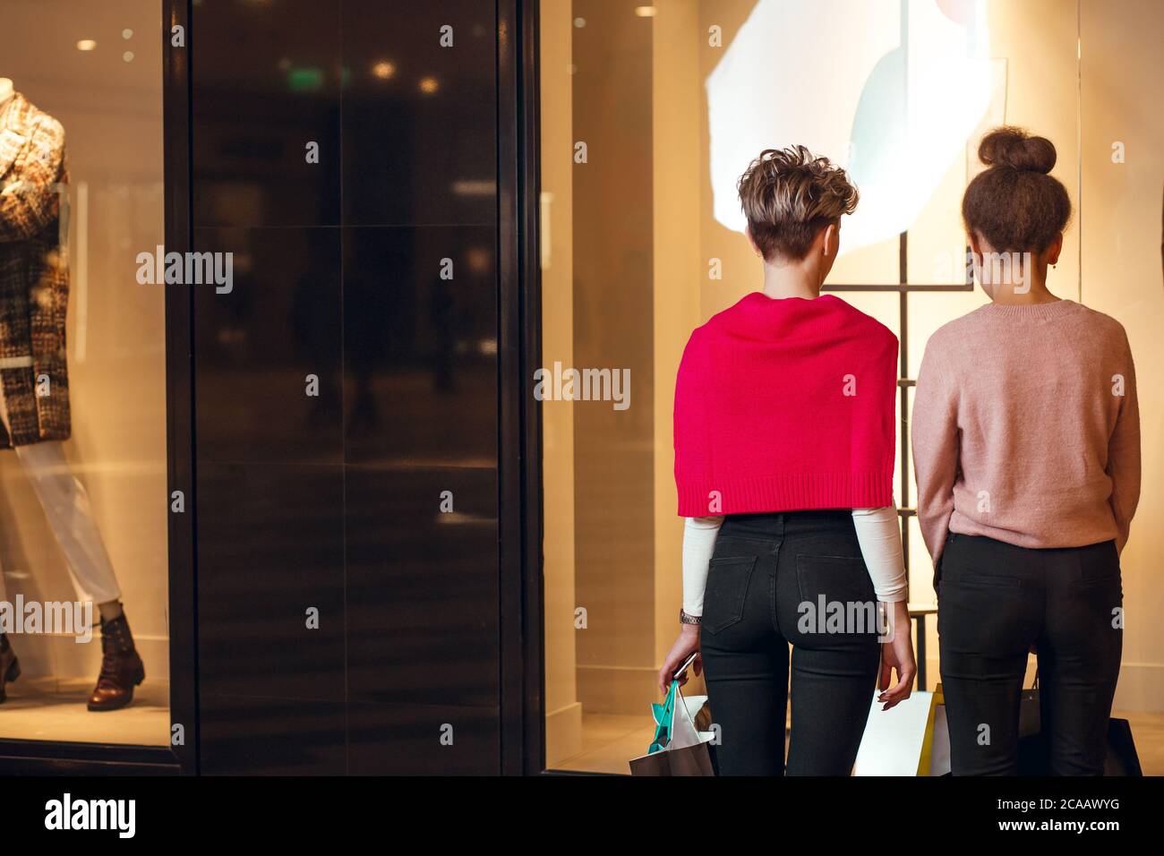 Zwei weibliche Shopoholic Freunde Blick auf Schaufenster der Lady s Wear Frauen Kollektion Boutique, Rückansicht. Stockfoto