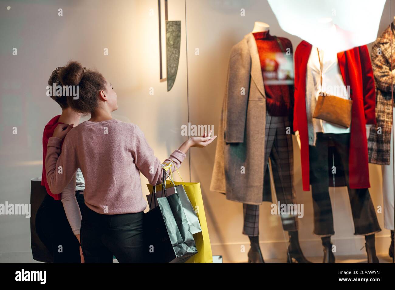 Zwei weibliche Shopoholic Freunde Blick auf Schaufenster der Lady s Wear Frauen Kollektion Boutique, Rückansicht. Stockfoto