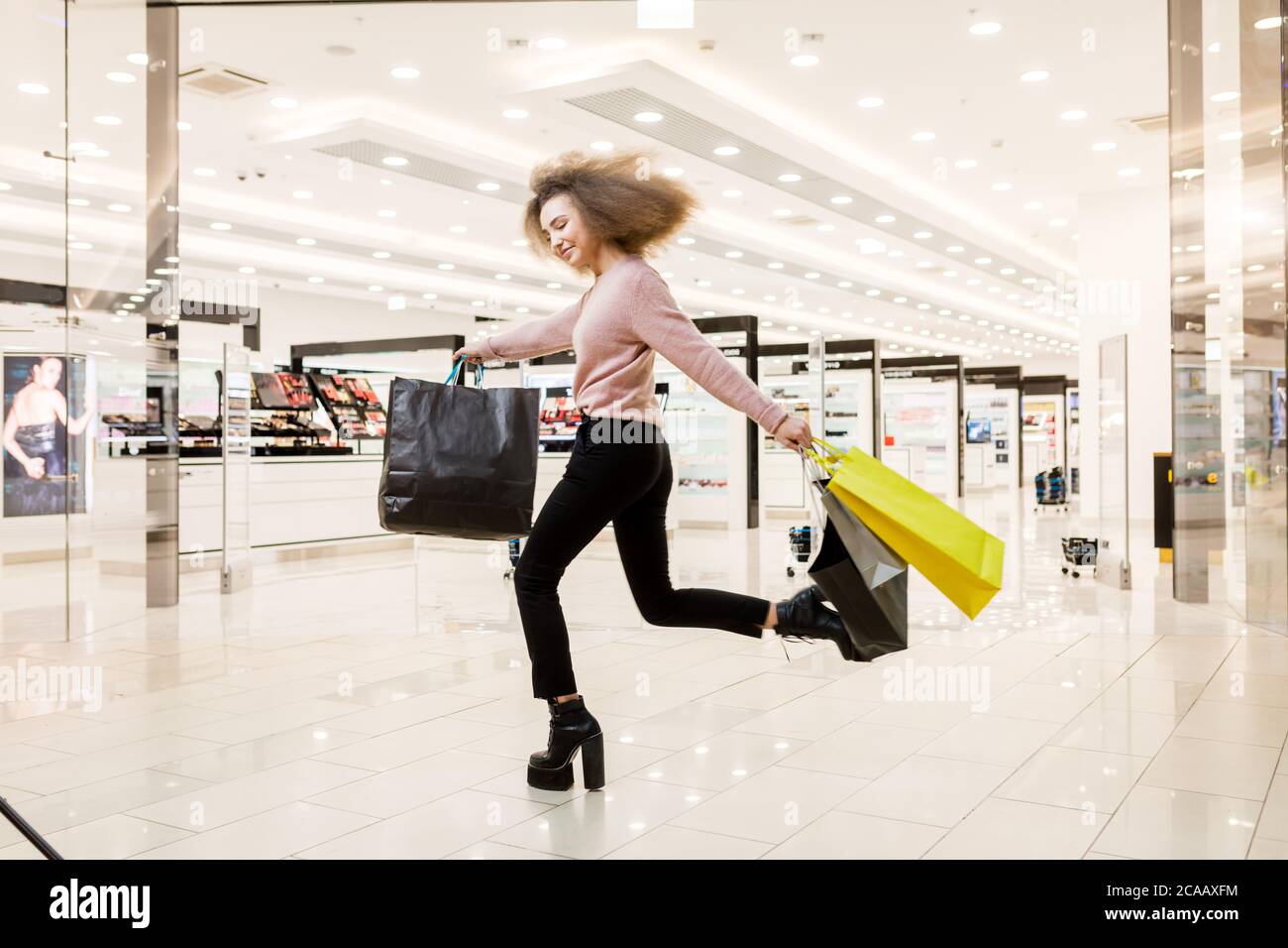 Aufgeregt junge weibliche Shopoholic läuft auf High Heels entlang der spacigen Einkaufszentrum, Rabatt Zeit beginnt. Stockfoto