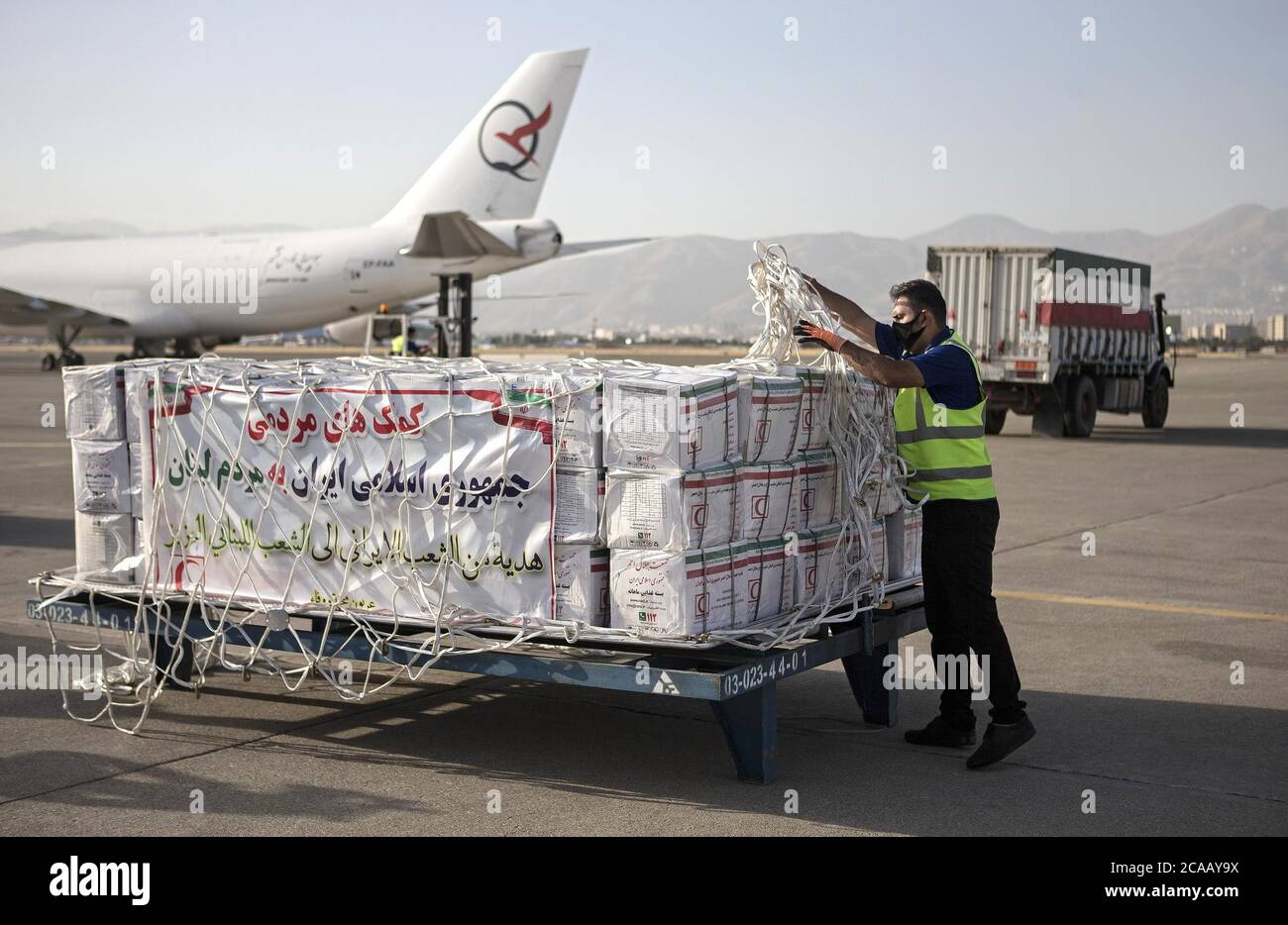 Teheran, Iran. August 2020. Ein Arbeiter bereitet sich darauf vor, am 5. August 2020 auf dem internationalen Flughafen Mehrabad in Teheran, Iran, Kisten mit Lebensmitteln und medizinischen Hilfsgütern in ein Flugzeug zu laden. Der Iran hat begonnen, Nahrungsmittel, Medikamente und medizinische Geräte nach den riesigen Explosionen im Hafen von Beirut in den Libanon zu schicken, berichtete Press TV am Mittwoch. Quelle: Ahmad Halabisaz/Xinhua/Alamy Live News Stockfoto