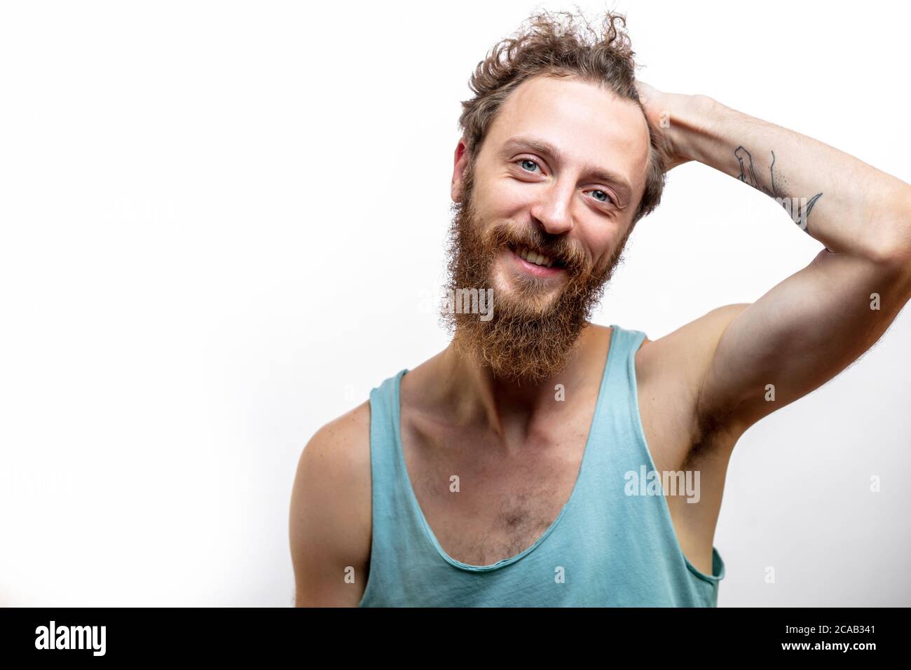 Porträt der jungen Hübschen hippie Mann mit Bart lächelnd an Kamera positiv, freundlich und selbstbewusst, vielversprechend, dass Client gemacht haben ein Recht Stockfoto