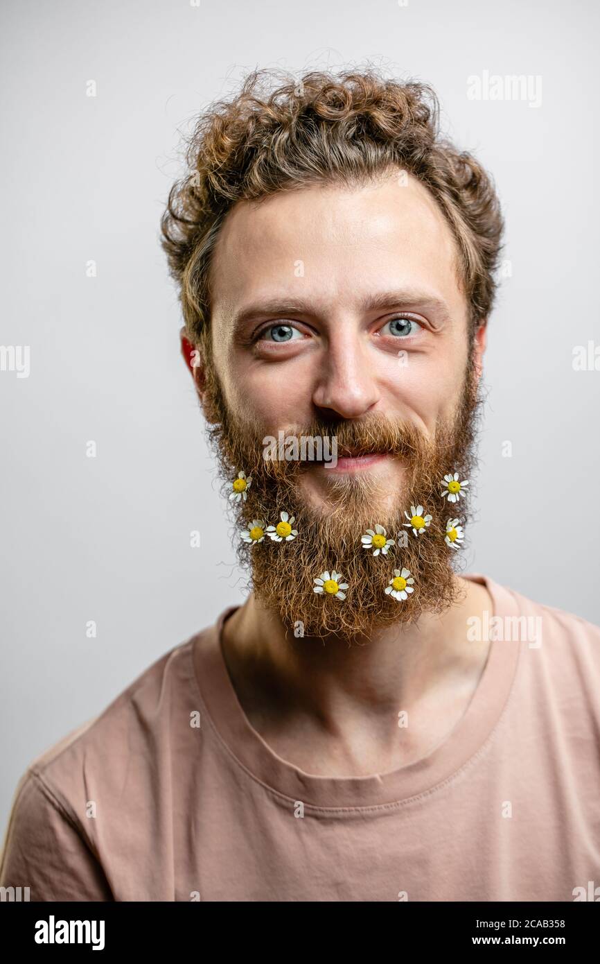 Angenehm, gutherzig glücklich Hipster Kerl lächelt an der Kamera, drückt positive Emotionen Sympathie und große Liebe. Fröhlicher romantischer Blumenmann mit dai Stockfoto