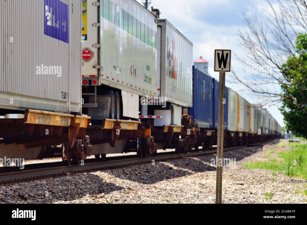 Mazon, Illinois, USA. Ein Burlington Northern Santa Fe Stack Zug brüllt durch Mazon, Illinois, während sie ein Hinweisschild passieren. Stockfoto