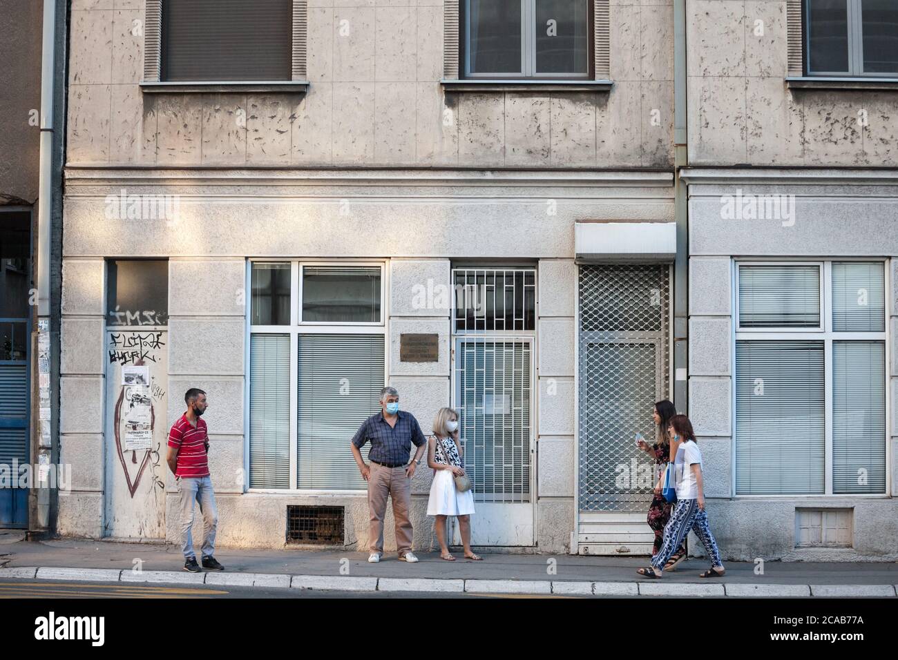 BELGRAD, SERBIEN - 21. JULI 2020: Vier Personen, jung und alt, Männer und Frauen, warten auf einen Laden auf einem Boulevard von Belgrad mit Gesichtsmaske pro betreten Stockfoto