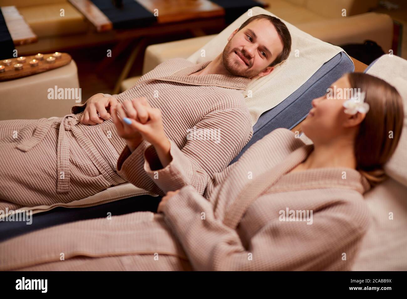 Kaukasische Ehepaar liegt auf Spa-Betten zusammen und nehmen die Hände von einander, in der Liebe Stockfoto