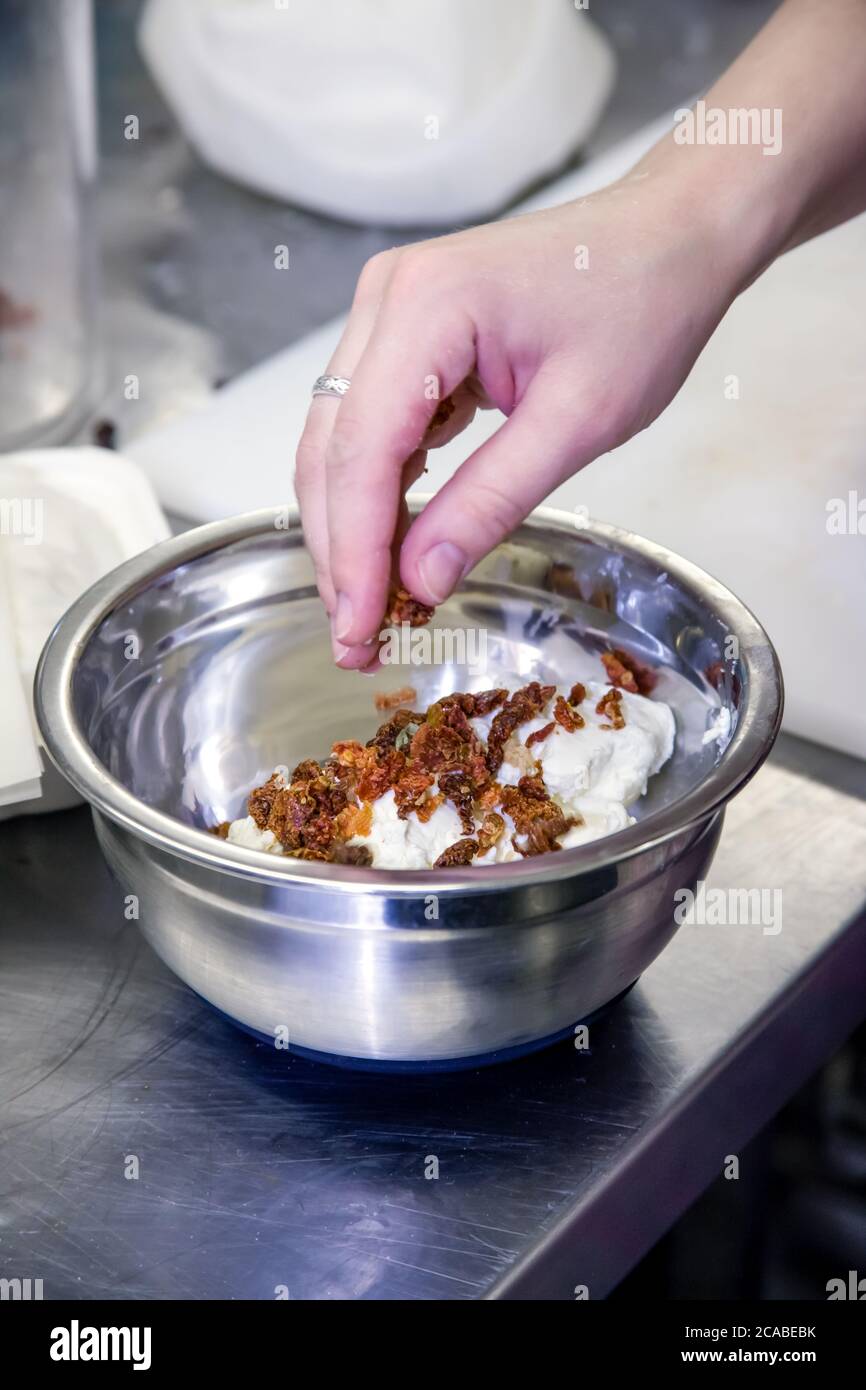 Frau, die getrocknete Aprikosen in Chevre-Käse hinzufügt, bevor sie ihn zu Käsereisten bildet, in Fall City, Washington, USA Stockfoto