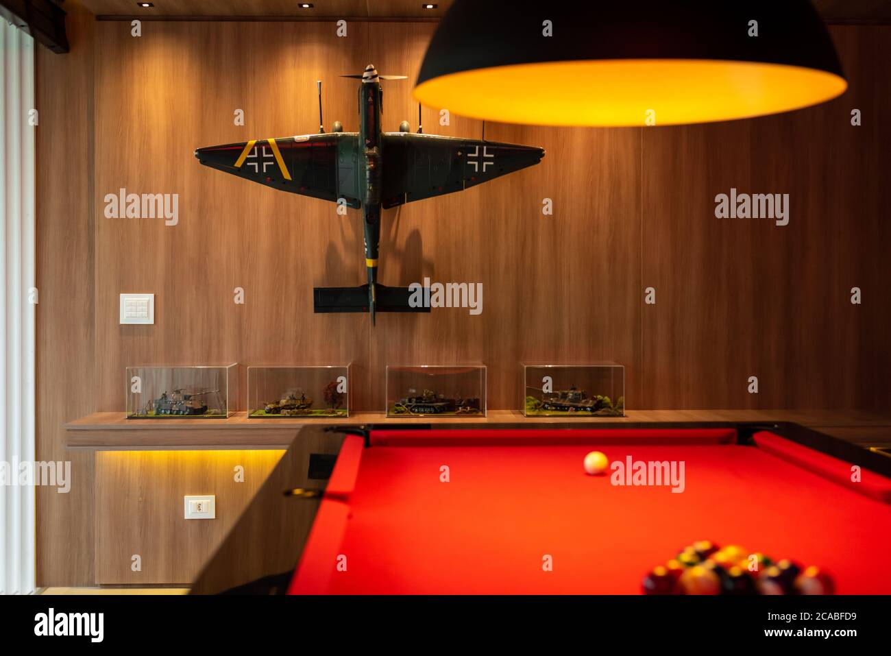 Roter Billardtisch auf einem Spielzimmer mit großen Fenstern Blick auf die Natur, Bulldog Neon-Schilder Stockfoto