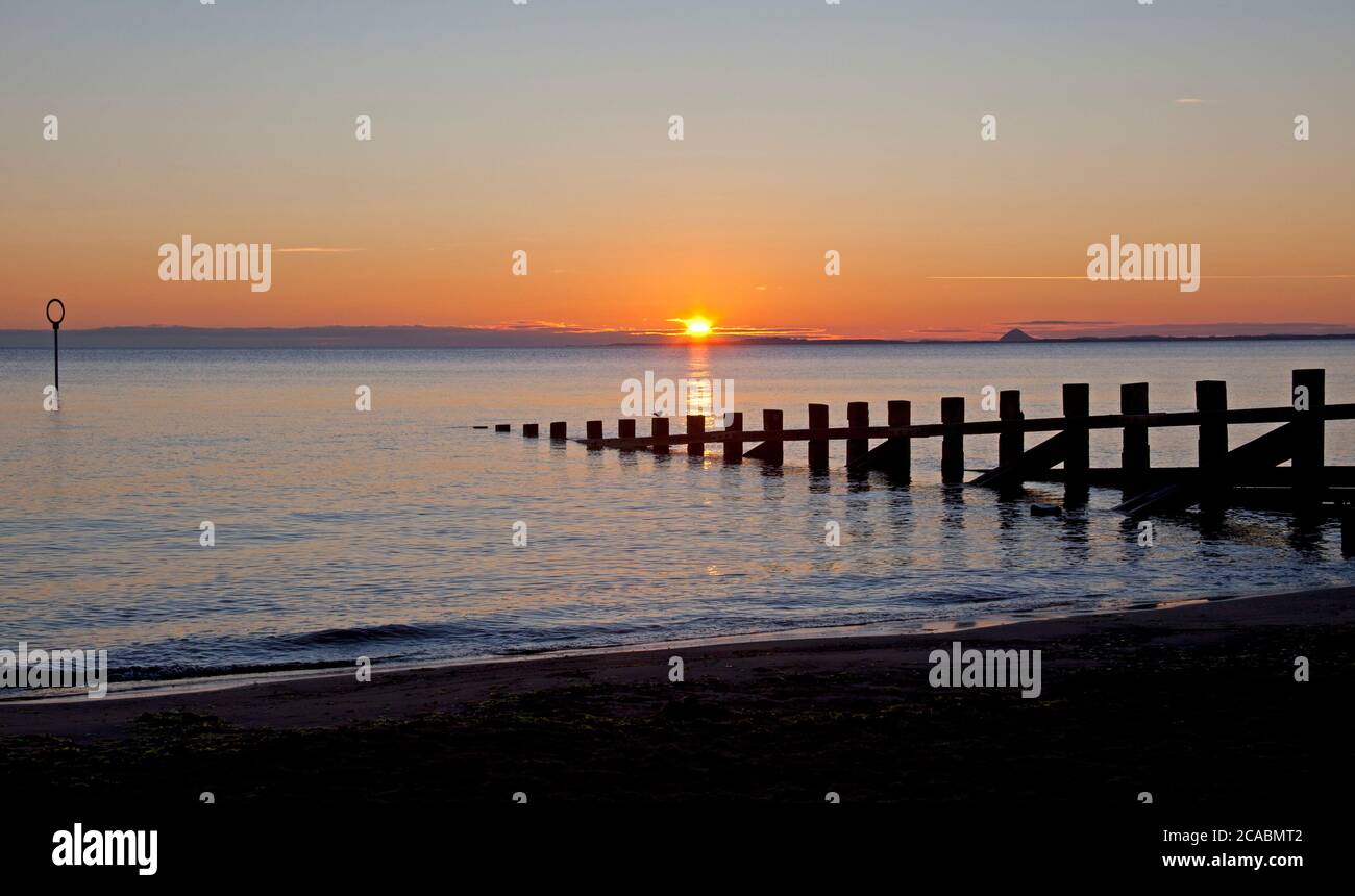 Portobello, Edinburgh, Schottland, Großbritannien. August 2020. Schöner Sonnenaufgang über dem Firth of Forth, Temperatur 12 Grad und Ruhe mit wenig oder gar keinem Wind, Vorhersage verbessert nach einem miserablen paar Tagen regen. Mit dem Strand groynes in Silhouette. Stockfoto