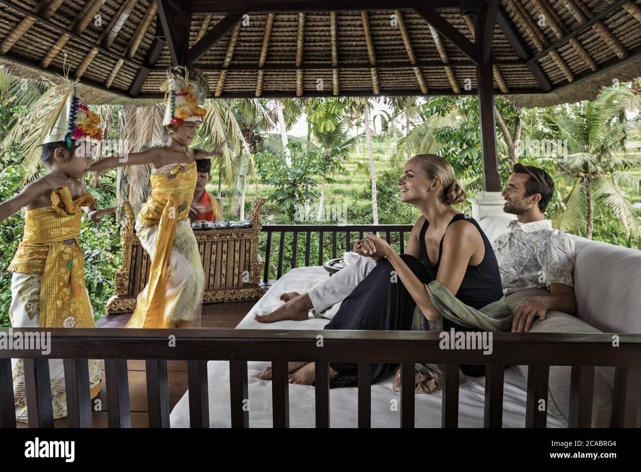 Asien, Indonesien, Bali, junges kaukasisches Paar, das elegante Freizeitkleidung trägt und einen traditionellen balinesischen Legong-Tanz mit Gamelon-Tradition genießt Stockfoto