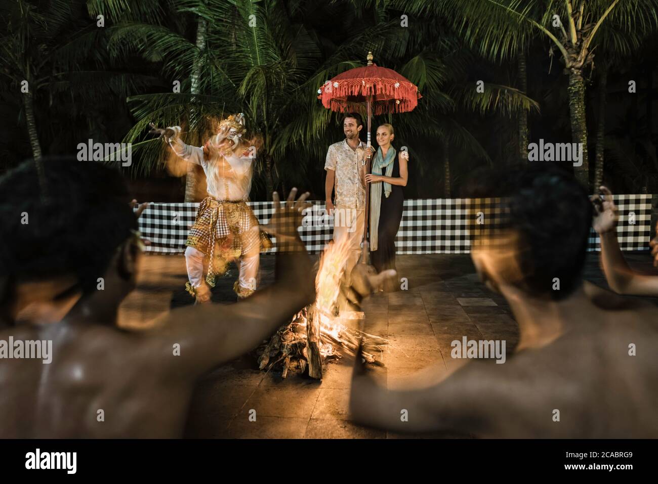 Asien, Indonesien, Bali, junges kaukasisches Paar, in eleganter Freizeitkleidung, genießen Sie einen traditionellen balinesischen Kecak-Tanz, der um ein Feuer herum aufgeführt wird Stockfoto