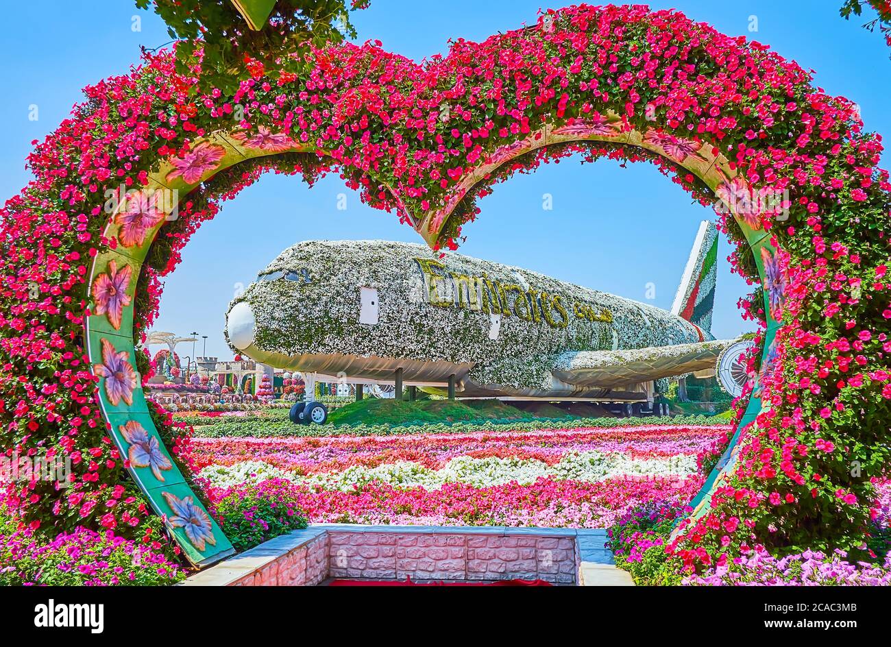 DUBAI, VAE - 5. MÄRZ 2020: Der herzförmige Bogen mit Petunien vor Emirates A380, bedeckt mit weißen Blumen und grünem Logo, Miracle Stockfoto