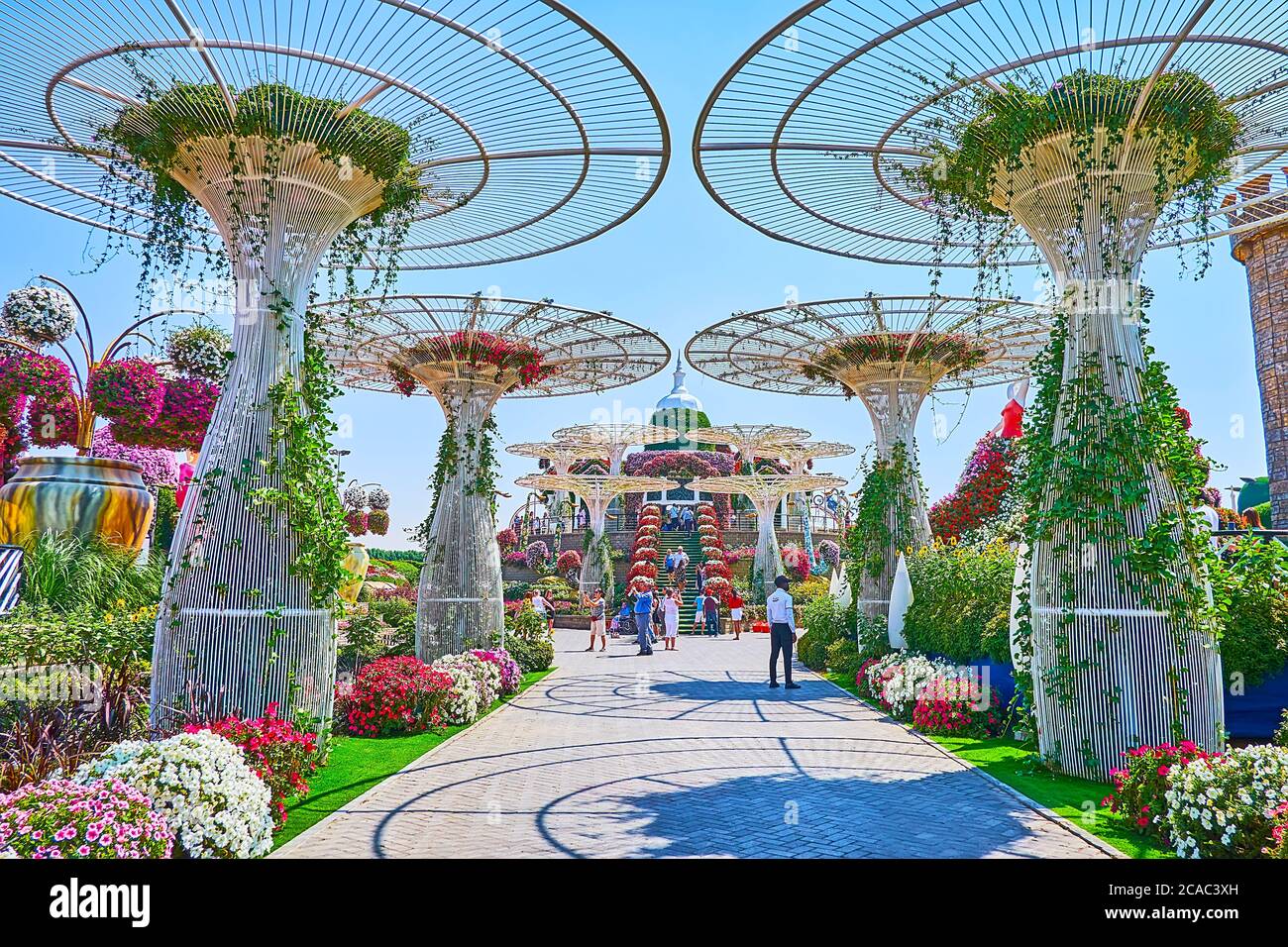 DUBAI, VAE - 5. MÄRZ 2020: Spazieren Sie durch die malerische Gasse mit riesigen Sonnenschirmen, Petunia-Blumenbeeten und Aussichtspavillon im Hintergrund, Miracle Garde Stockfoto