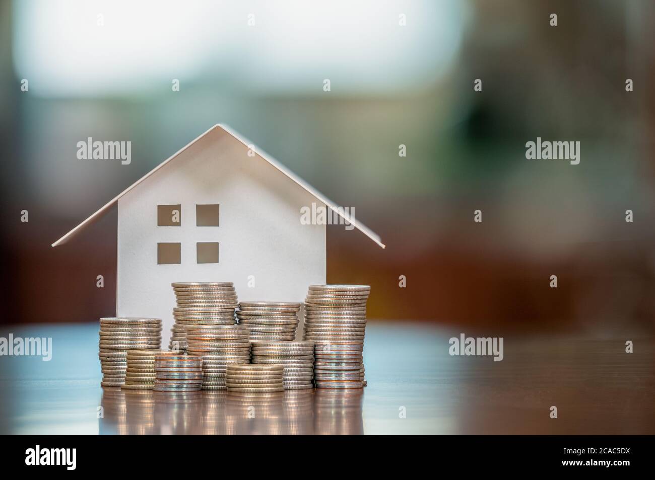 Modellhäuser und gestapelte Münzen. Eigenheimkredite. Hypotheken und Darlehen. Stockfoto