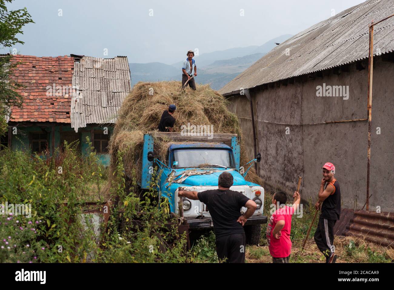 Alaverdi / Armenien - 20. Juli 2019: Armenische Männer, die auf dem Feld arbeiten und Stroh in alte sowjetische Lastwagen verladen Stockfoto