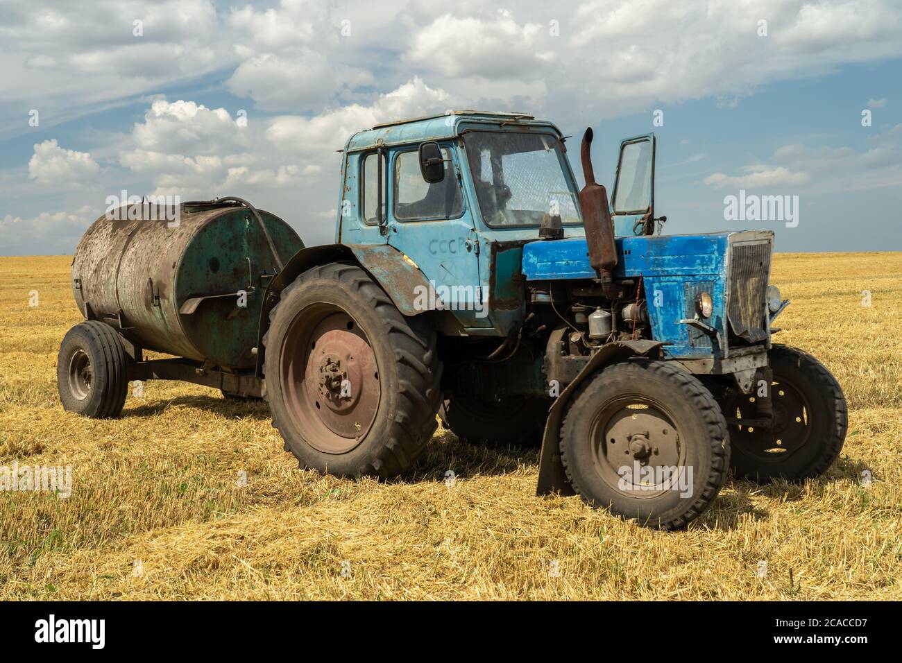 Ein alter seltener Traktor fuhr ein Fass Dieselkraftstoff auf das Feld, Stockfoto