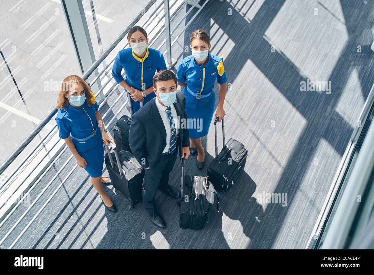 Vier Flugbegleiter in Masken schauen nach oben Stockfoto