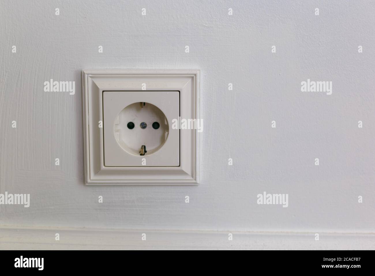 Weißer Kunststoffausgang mit Erdung auf grauem Hintergrund. Wand mit Kopierbereich. Minimalismus. Stockfoto
