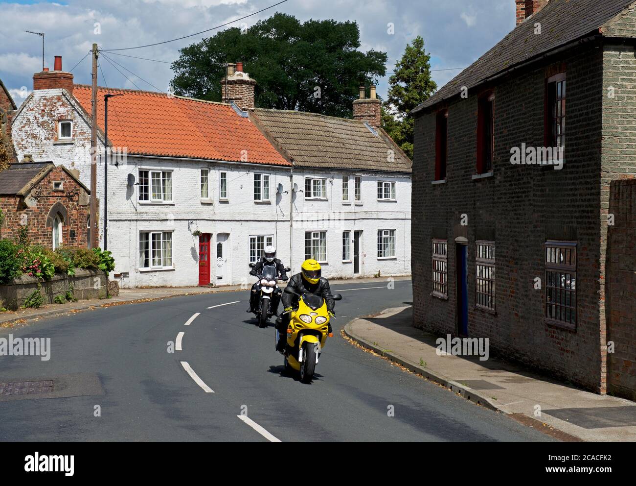 Zwei Biker runden Kurve im Dorf Airmyn, East Yorkshire, England Großbritannien Stockfoto