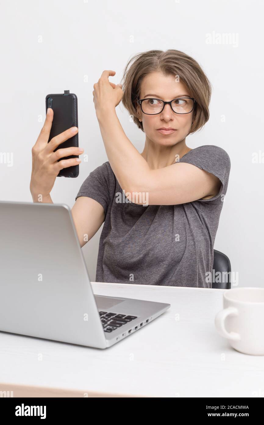 Eine Bloggerin hält ein Smartphone in der Hand und bereitet sich auf eine Online-Konferenz vor. Stockfoto