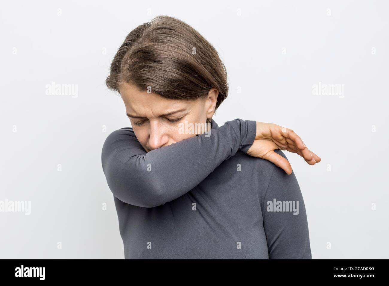 Frau hustet hinter ihrer Hand. Stockfoto